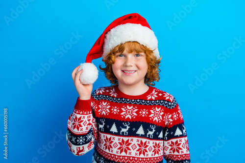 Photo of positive cute little boy dressed ugly pullover x-mas hat smiling isolated blue color background