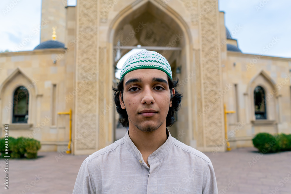 Fototapeta premium portrait of a young man of Muslim appearance leaving the mosque after prayer on terrace with Islamic ornaments 