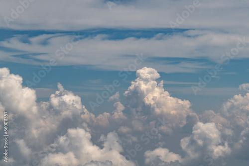 White fluffy clouds against a blue sky as seen from a plane 