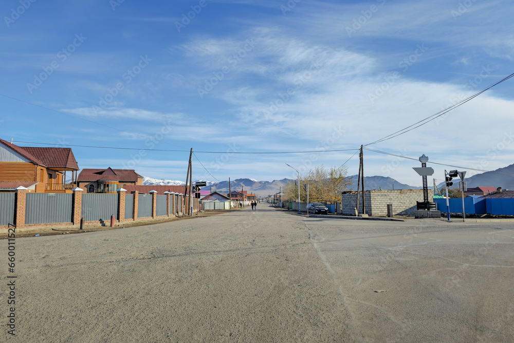 Northern Mongolia. City of Ulgiy. Houses of the street stretching into the distance to the mountains, Mongolian people on the street are busy with their worries. Northern Mongolia. City of Ulgiy. Houses of the street stretching into the distance to the mountains, Mongolian people on the street are busy with their worries.