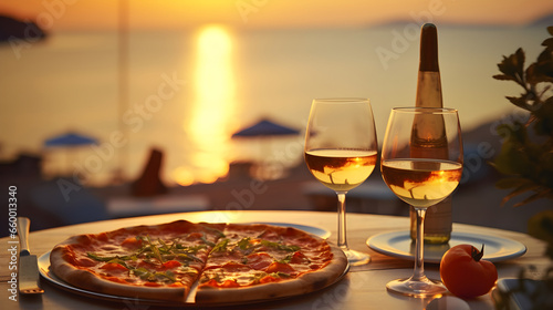 Pizza with white wine glasses at a seaside restaurant at sunset