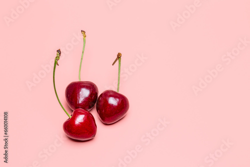 Red cherries on a pink background. Copy space for text.  © Gennadi