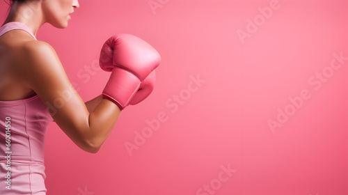 Woman with pink boxing gloves hooking or fighting against pink wall, Breast cancer awareness concept