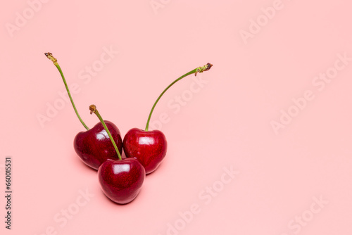 Cherries on a pink background with copy space for text. 