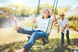 Woman, happy and fun on swing in retirement, playful and joy in summer vacation for quality time. Elderly people, support and love in relationship, funny and laugh for silly, goofy and holiday