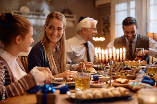 Happy Jewish woman talks to her daughter during family meal on Hanukkah.
