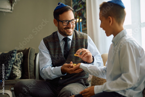 Happy father giving Hanukkah gelt to his son while celebrating Jewish festival of lights. photo