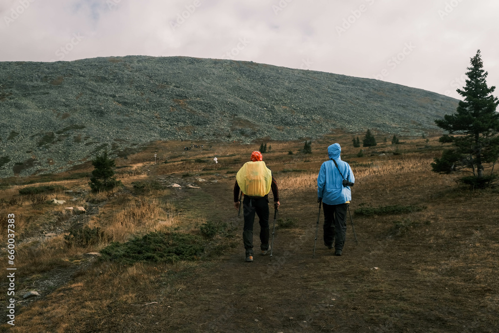 Naklejka premium active lifestyle.A man with a tourist backpack and a photographer girl go to the top of the mountain.Hiking in the mountains
