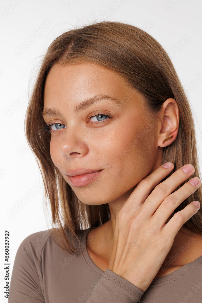 Beautiful young girl with fresh healthy skin. Woman advertise ear-rings. White background. Earrings, ear caffs closeup. Blond european woman with long hair with big lips, pretty smile. Cosmetology