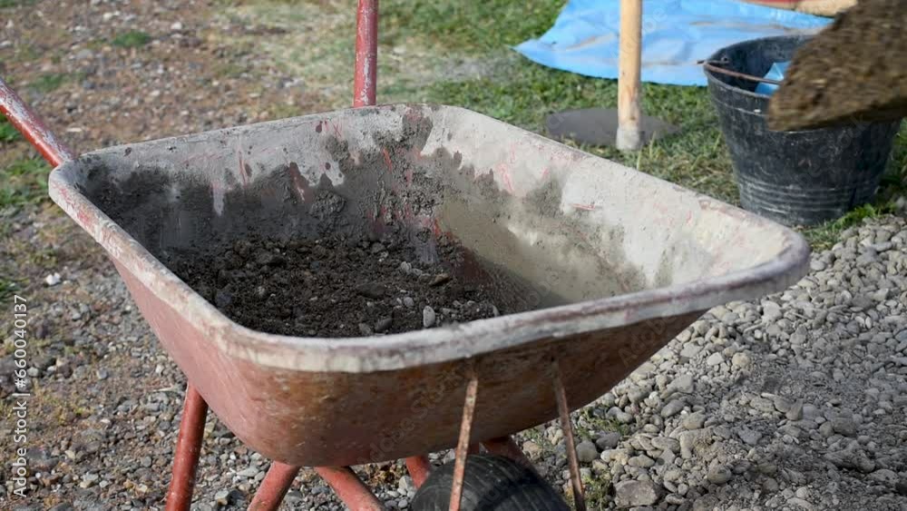 Man grabbing gravel in a wheelbarrow, hard work Man grabbing gravel in a wheelbarrow, hard work