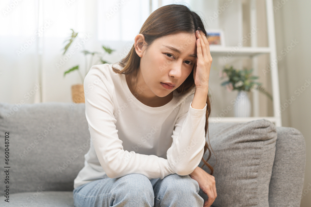 Dizzy asian young woman, girl headache or migraine pain suffering from vertigo while sitting on couch in living room at home, holding head with hand, health problem of brain or inner ear not balance. Dizzy asian young woman, girl headache or migraine pain suffering from vertigo while sitting on couch in living room at home, holding head with hand, health problem of brain or inner ear not balance.