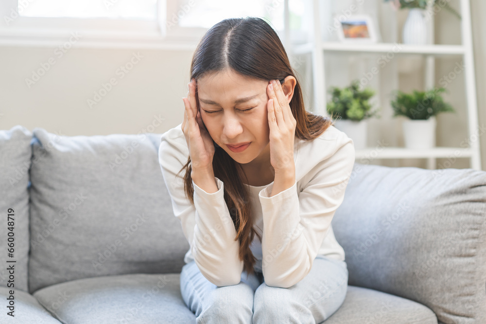 Dizzy asian young woman, girl headache or migraine pain suffering from vertigo while sitting on couch in living room at home, holding head with hand, health problem of brain or inner ear not balance. Dizzy asian young woman, girl headache or migraine pain suffering from vertigo while sitting on couch in living room at home, holding head with hand, health problem of brain or inner ear not balance.