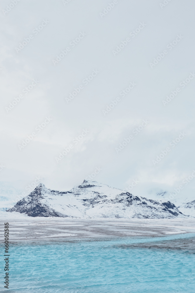 A mesmerizing Icelandic landscape showcasing a blue lagoon, vast frozen lake, snow-covered mountains