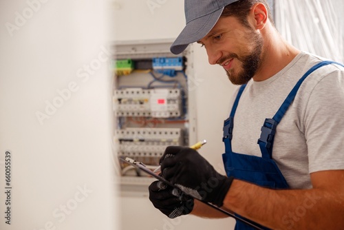 Busy electrical technician writing on a clipboard the data collected on a residential electric panel