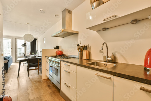 Fototapeta Naklejka Na Ścianę i Meble -  a kitchen and dining area in a house with wood floors, white cabinets and stainless steel appliances on the wall