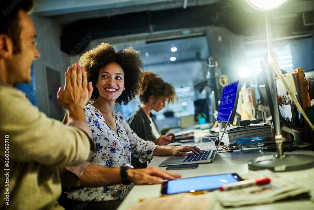 Young woman high fiving a colleague in a modern office Young woman high fiving a colleague in a modern office