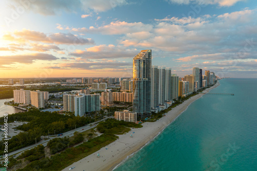 Aerial view of Sunny Isles Beach city with luxurious highrise hotels and condos on Atlantic ocean shore at sunset. American tourism infrastructure in southern Florida