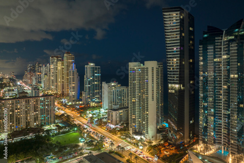 Night urban landscape of downtown district in Sunny Isles Beach city in Florida  USA. Skyline with brightly illuminated streets and high skyscraper buildings in modern american megapolis