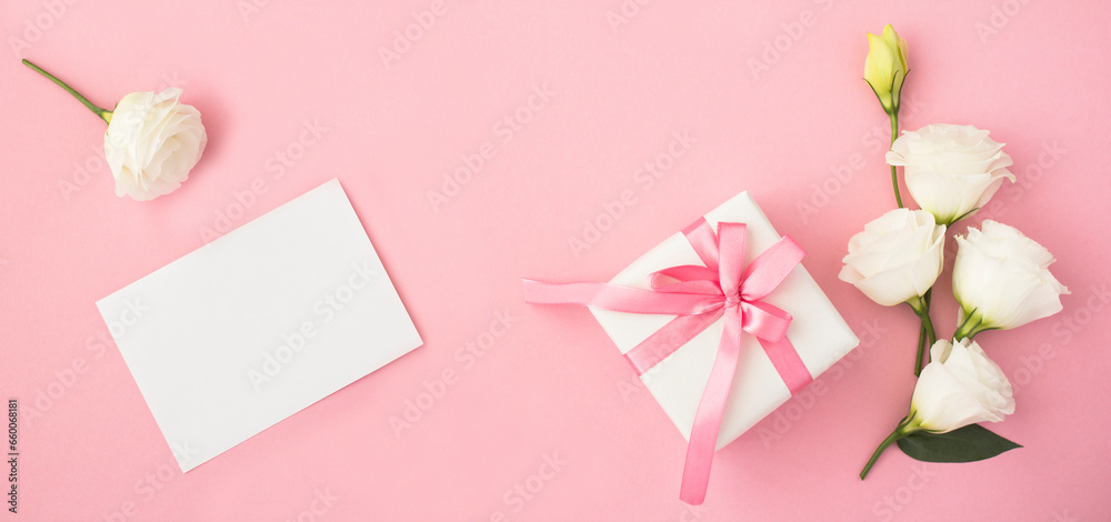 Empty white paper for text, gift box and beautiful white flowers on the pink  background. Top view. Copy space.