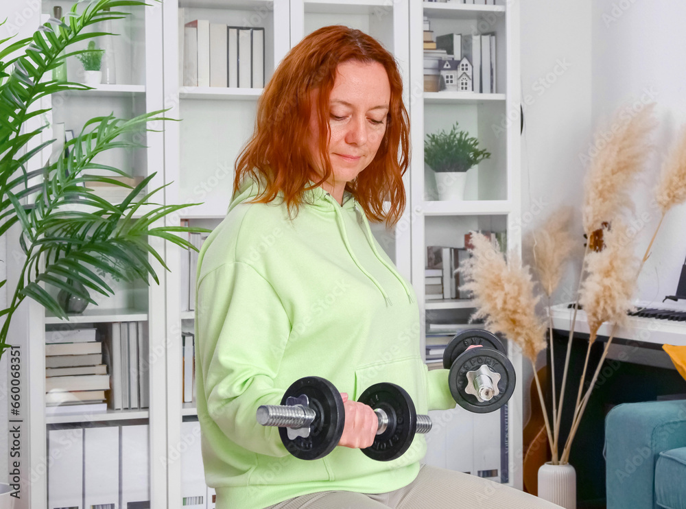 woman doing sports exercises with fitness ball and dumbbells at home