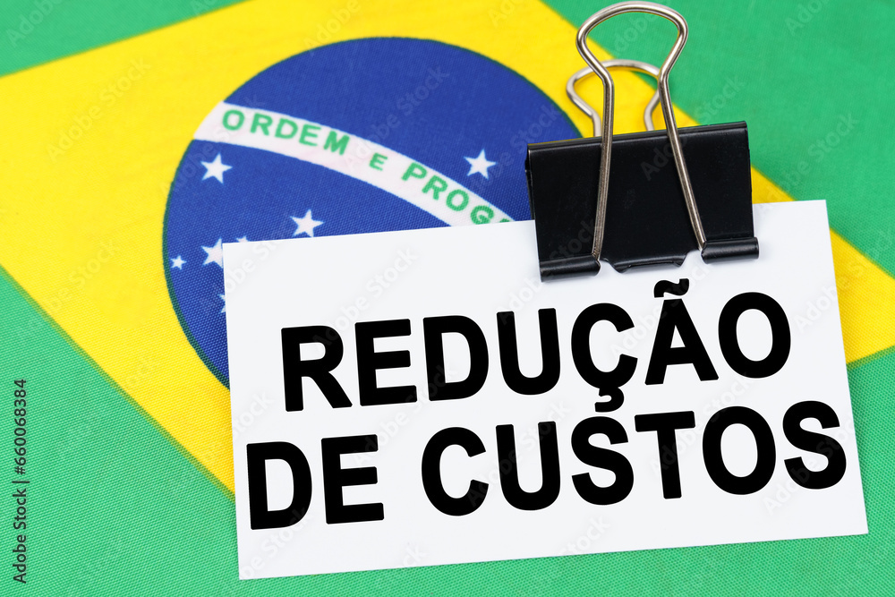 Φωτογραφία On the flag of Brazil lies a business card with the inscription - cost reduction