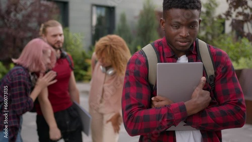 Sad upset offended victim boy student guy African American suffering man bullied of group multiracial students teens classmates thumb down mocking bully abused bullying university college aggression