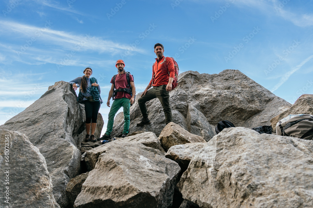 A group of climbing friends, smiling and looking at the camera at the top of the rock.
