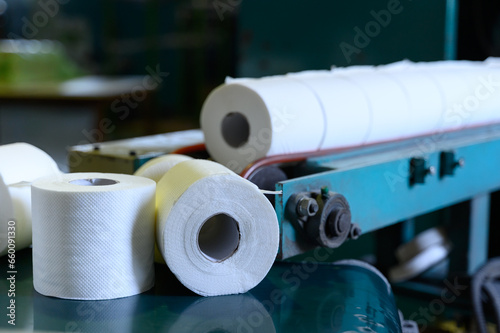 Toilet paper rolls moving along the conveyor belt. Old Greek factory for the production of paper rolls for hygiene. Manufacture of paper towels and toilet paper. Close up view. Selective focus
