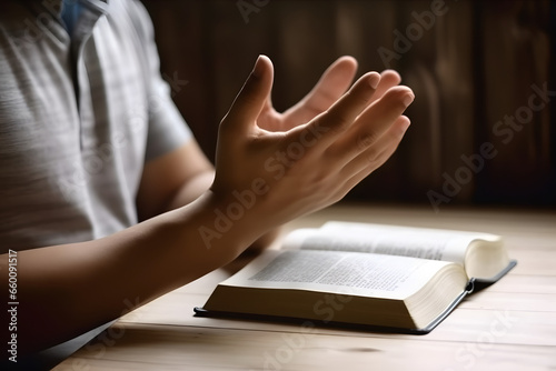 Hands together in praying to God along with the holy bible book