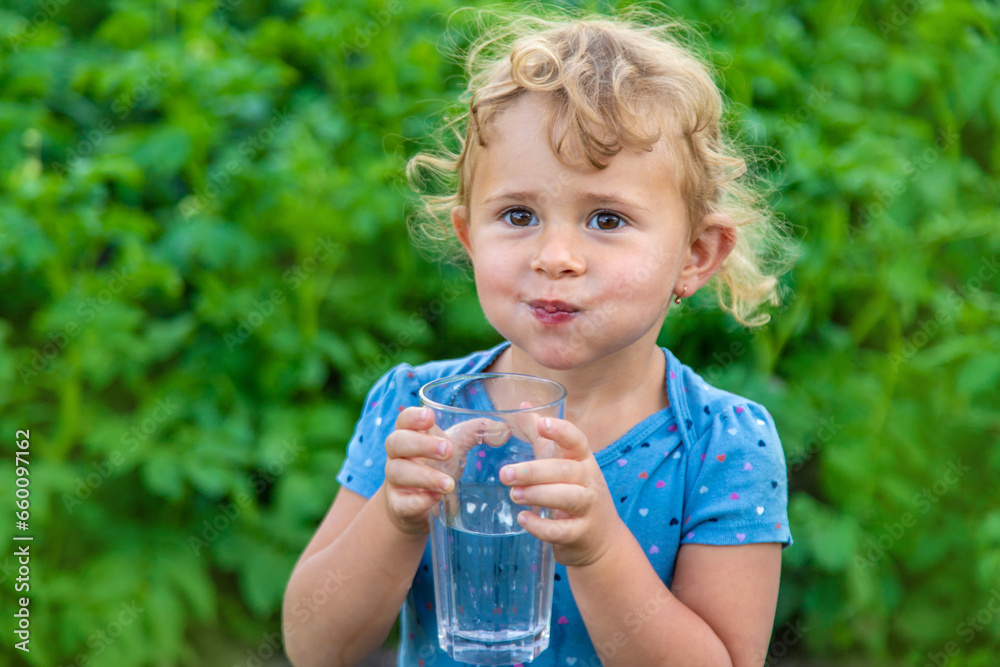 A child drinks water from a glass. Selective focus. A child drinks water from a glass. Selective focus.
