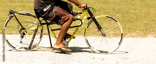 Bicicleta customizada sendo pedalada por pés usando chinelos no parque.  photo