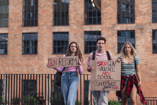 Generation Z activists with banners protesting on the street. Young students marching through the city demonstrate against climate change. Protesters demanding gun control, racial and gender equity.