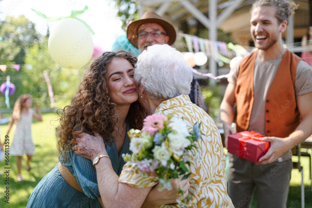 Garden birthday party for senior lady. Beautiful senior birthday woman hugging granddaughter. Garden birthday party for senior lady. Beautiful senior birthday woman hugging granddaughter.