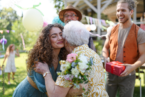 Garden birthday party for senior lady. Beautiful senior birthday woman hugging granddaughter. © Halfpoint