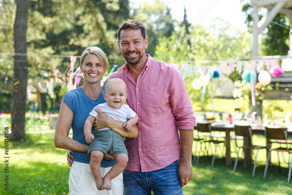 Young family with baby at family garden party. Father, mother, and small child at birthday party.