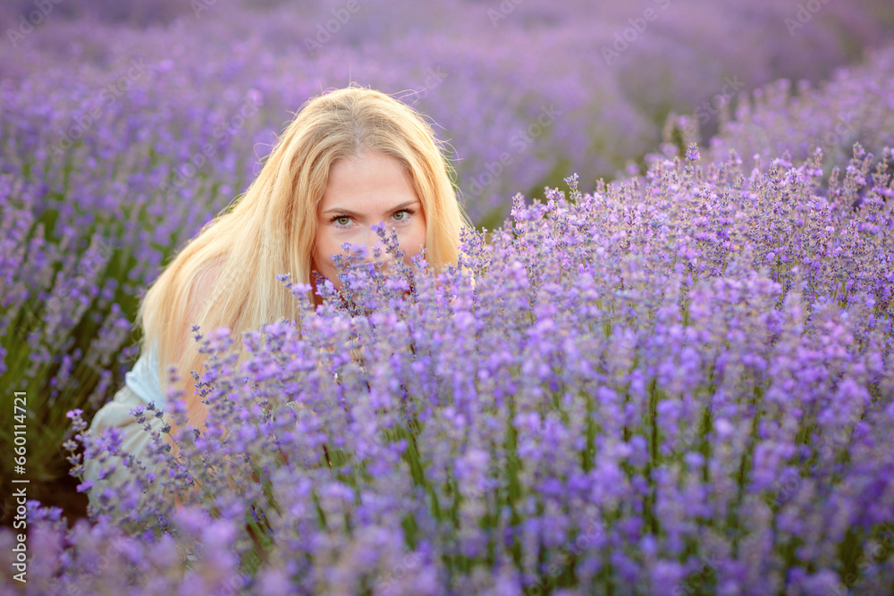 Lavender field. Young attractive woman with blond hair walking between rows of lavender flowers, posing for camera, relaxing, resting, enjoying nature, smelling and touching flowers. Mental health Lavender field. Young attractive woman with blond hair walking between rows of lavender flowers, posing for camera, relaxing, resting, enjoying nature, smelling and touching flowers. Mental health