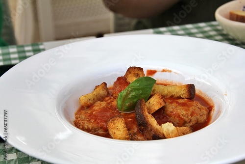 plate with meatballs, tomato sauce, pieces of dry sliced bread, fresh basil, Italian cuisine