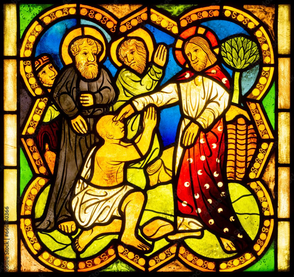 Stained glass church window with scenes of mercy and the lives of saints	
