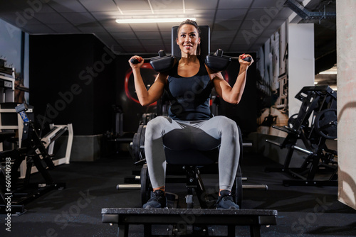 A strong woman is exercising on a exercise machine in a gym.
