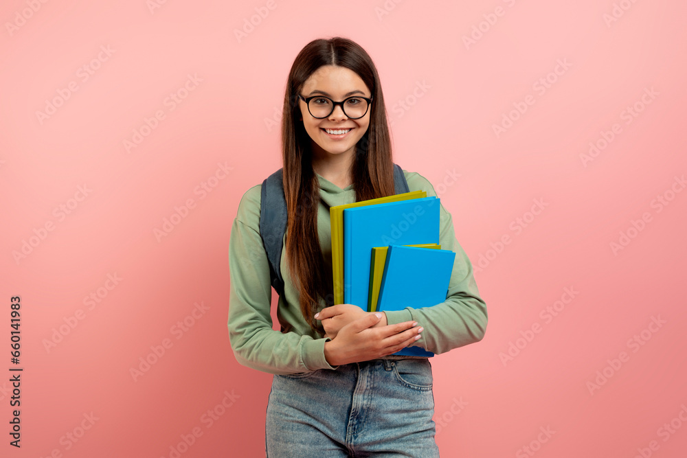 Portrait of smiling teenage girl student with backpack, workbooks, and eyeglasses Portrait of smiling teenage girl student with backpack, workbooks, and eyeglasses