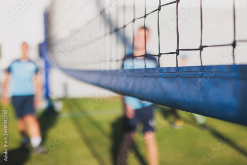 Volleyball game, junior teenage school team of kids play volleyball, players on the outdoor playground with net and green lawn grass court, sports children team during the game, summer sunny © tsuguliev