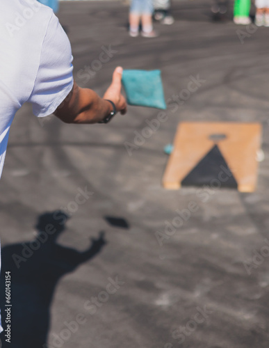 Cornhole game set, process of throwing bean bags, kids children tossing bean sacks, corn hole  in the backyard, wooden boards for corn-hole tournament in the summer sunny day