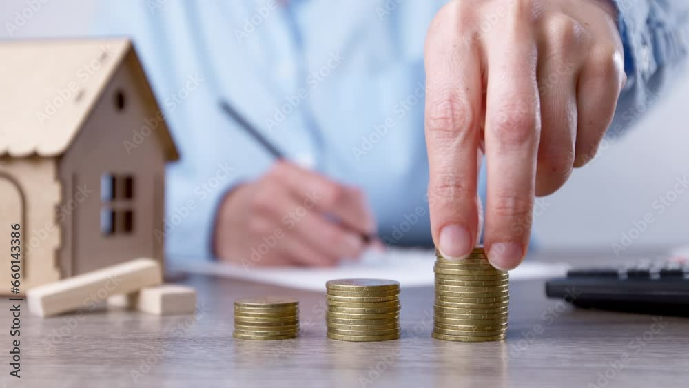 Saving money to buy a house. Coins in a woman's hand as an investment in real estate. Mortgage concept.