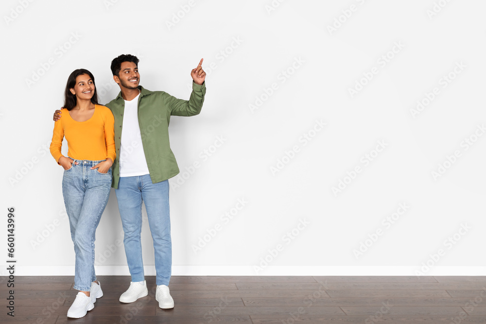 Indian couple hugging, pointing to free space