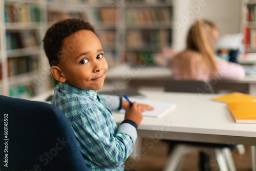 Smiling african american boy in class turning back towards camera photo