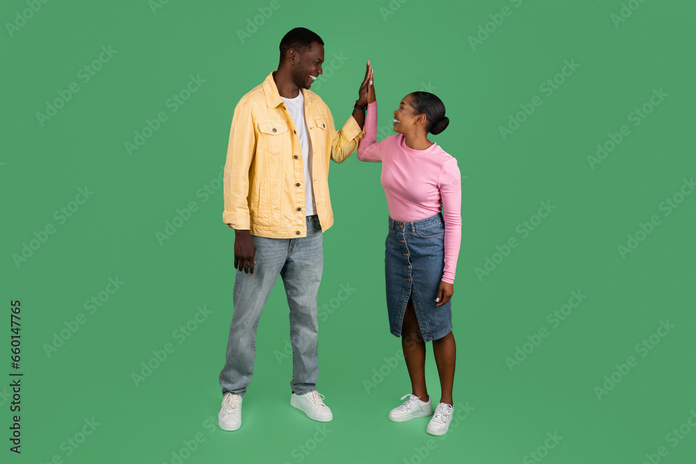 Positive black man and woman giving each other high five