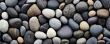 Closeup of speckled pebbles on the riverbed These pebbles have a speckled appearance due to their dark, almost black coloration with small, white spots. The riverbed is mostly dark and rocky,