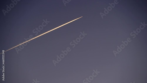 Airplane at cruising altitude with contrail against sky. Chemtrails or condensation trails. Time lapse