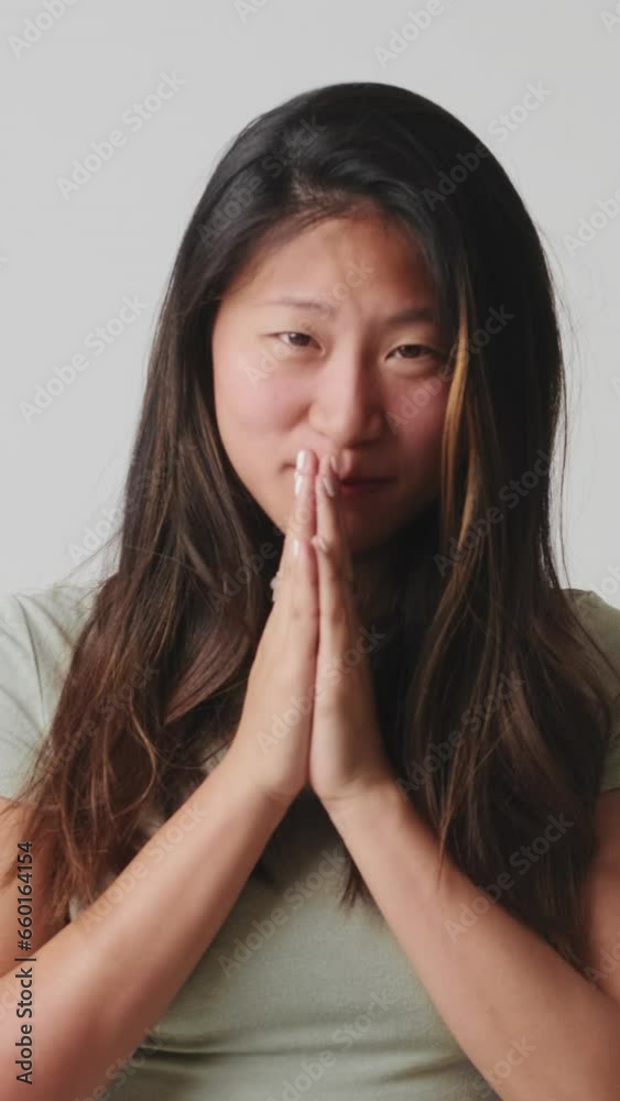Young woman hold hands folded in prayer, making wish isolated over white background in studio Young woman hold hands folded in prayer, making wish isolated over white background in studio