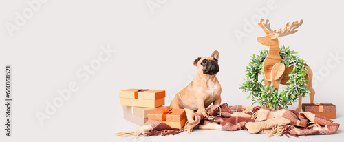Cute dog with Christmas gifts, plaid wooden deer and wreath on light background with space for text